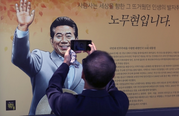 노무현 전 대통령 서거 10주기 추도식을 하루 앞둔 22일 오후 경남 김해시 진영읍 봉하마을에서 한 시민이 휴대폰으로 노 전 대통령 초상화를 촬영하고 있다.