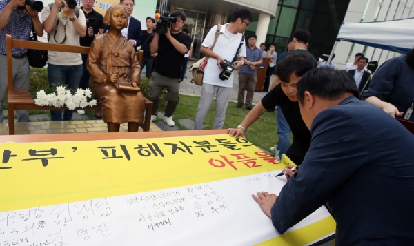 14일 오전 광주 서구청 앞 평화의소녀상 앞에서 열린 일본군 위안부 피해자 기림의 날 기념행사에서 참가자들이 위안부 피해자분들의 아픔을 기억하겠다는 대형 현수막에 서명을 하고 있다.