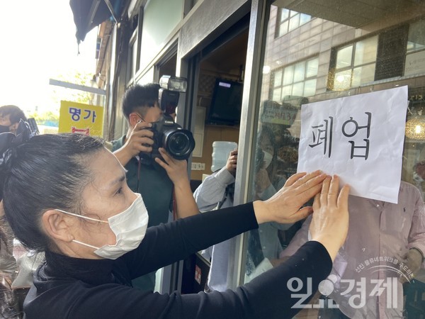 18일 서울 동작구에서 고깃집 '흑돈연가'를 운영했던 소상공인 손원주 씨가 코로나19로 경영난을 겪으며 가게 문 앞에 폐업 안내문을 붙이고 있다.