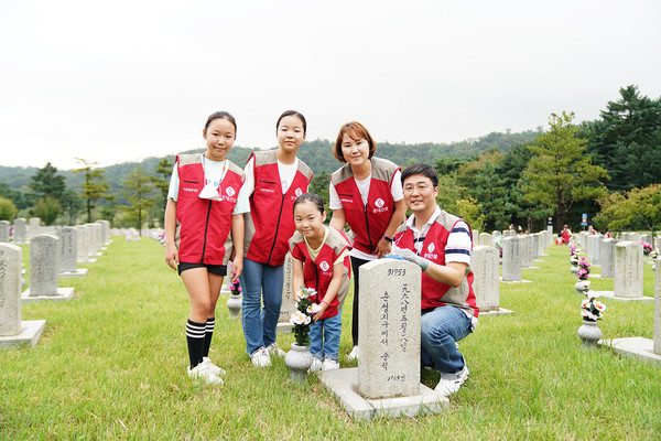 롯데건설 임직원과 가족들이 자매결연 묘역에서 봉사활동 후 기념 촬영을 하고 있다.(사진-롯데건설)